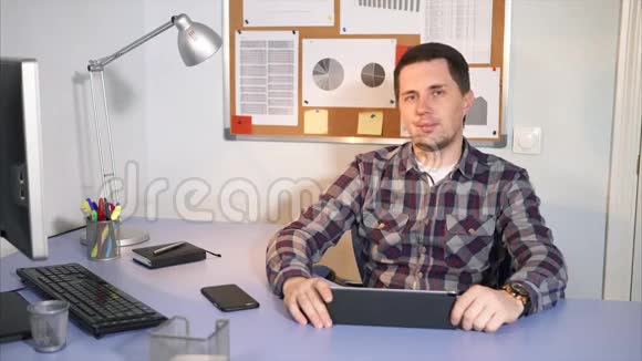 公司的经理坐在桌旁桌上放着平板电脑手机视频的预览图