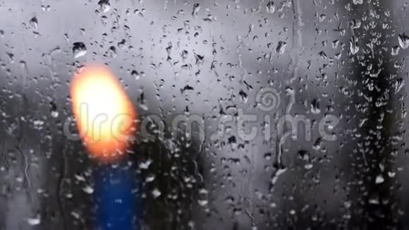 雨滴落在雨天的窗户上前景中有一支模糊的蜡烛视频的预览图