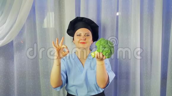 一个穿着围裙做饭的女人微笑着手里拿着西兰花露出她的手好吗视频的预览图