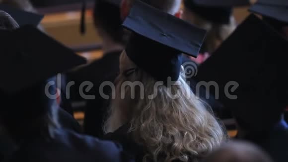 兴奋的金发女郎穿着黑色连衣裙和帽子为老师的演讲鼓掌视频的预览图