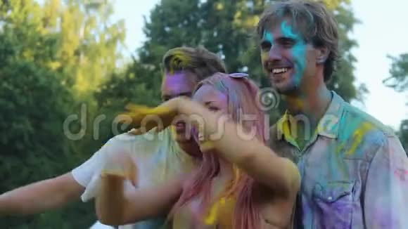 微笑的朋友用粉末涂料着色玩得开心摆姿势拍照视频的预览图