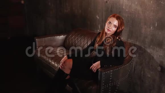 红头发的年轻女子坐在时髦的皮沙发上视频的预览图