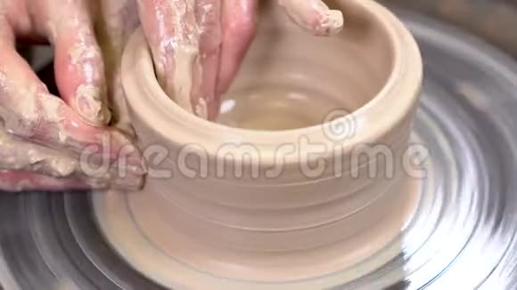 一只泥泞的手的特写在旋转的陶工的车轮上创造了一个陶器视频的预览图