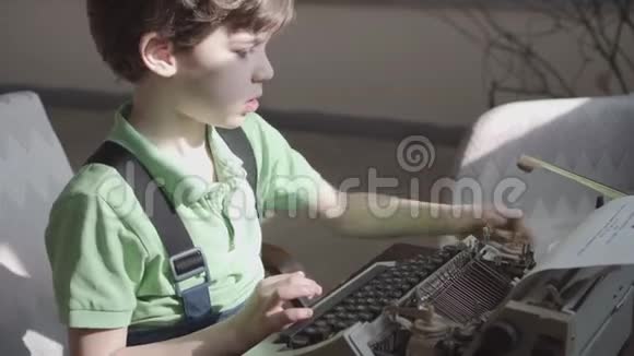 六岁的小男孩很高兴学习一台旧打字机的工作视频的预览图
