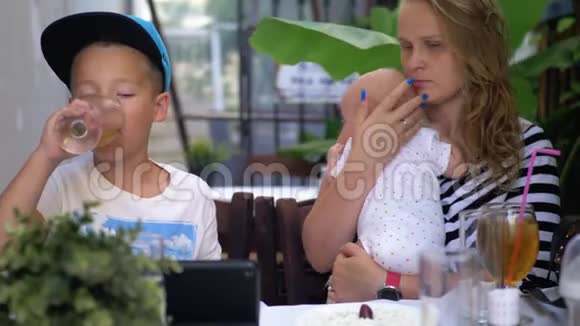 妈妈带着小女儿和大儿子在街头咖啡馆视频的预览图