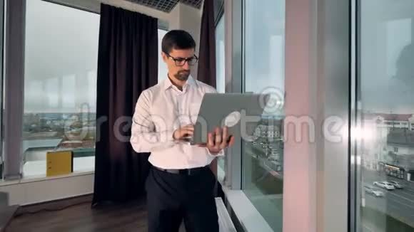 一个拿着笔记本电脑的商人回到办公桌旁视频的预览图