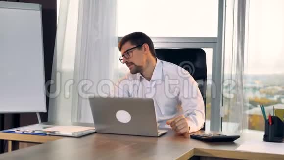 一个悲伤的商人盯着他的笔记本电脑屏幕视频的预览图