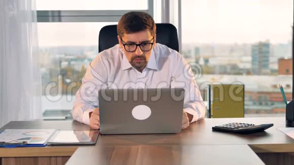 一个商人盯着笔记本电脑屏幕的字体视图视频的预览图