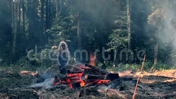 一位年轻女子站在火旁举起双手放下视频的预览图