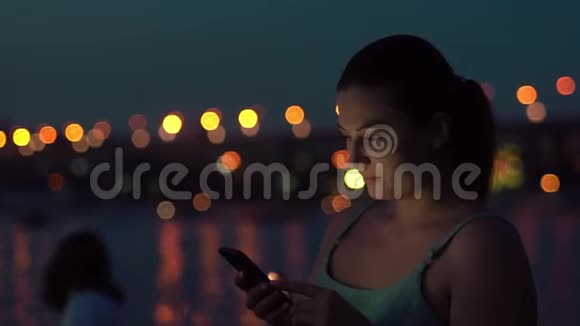 女孩在夜市散步时用智能手机视频的预览图