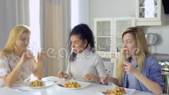 白种人的女朋友在厨房里吃沙拉和聊天视频的预览图