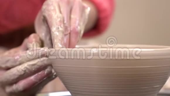 特写侧面的泥手塑造一个粘土器皿在旋转陶工的车轮视频的预览图