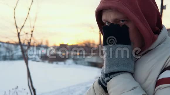 冬天一个年轻人冻僵地站在城市景观上的肖像视频的预览图