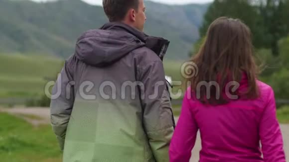 两个人在山的背景下散步蜜月男人和女人牵手在大自然中行走一对夫妇视频的预览图