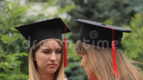 毕业典礼后两名女毕业生穿着学术服装交谈视频的预览图