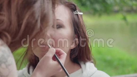 化妆师在拍照前把口红涂女孩的嘴唇上视频的预览图