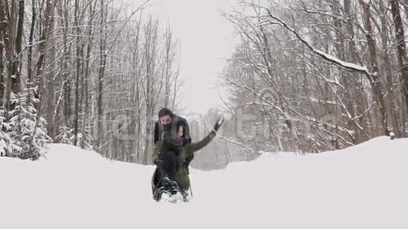 在阳光明媚的冬日里年轻的夫妇滑着雪橇享受着快乐慢动作视频的预览图