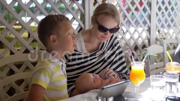 夏日咖啡馆里有婴儿和大孩子的女人视频的预览图
