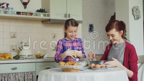 可爱的女孩在厨房里帮她妈妈把面团搅拌成饼干妈妈很开心给女儿抹鼻子视频的预览图