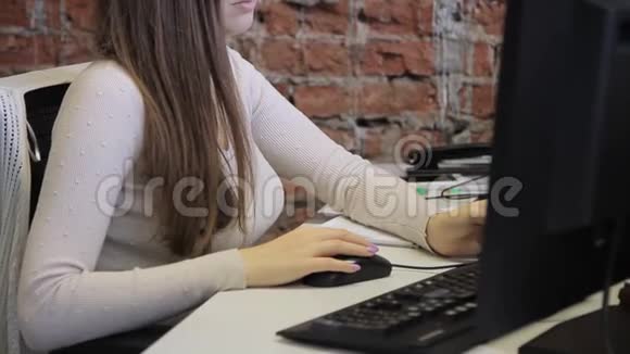 这位年轻女士在电脑上工作把鼠标拖到轻木桌上视频的预览图