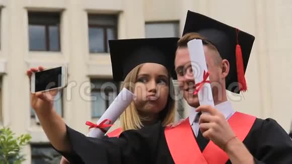 穿着学院服的搞笑学生在电话里自拍毕业典礼视频的预览图
