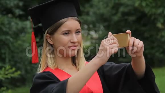 身着学院装的美女在智能手机上拍摄朋友毕业快乐视频的预览图