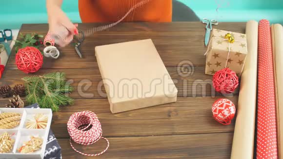 女性双手将圣诞礼物包裹在黑色木制背面的手工生态纸上视频的预览图
