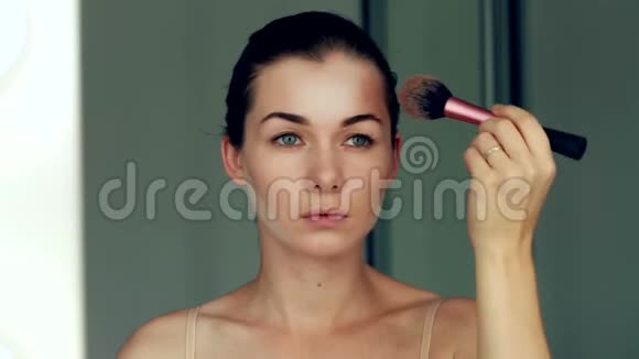 美女模特女孩照镜子化妆漂亮的年轻女人用刷子化妆视频的预览图