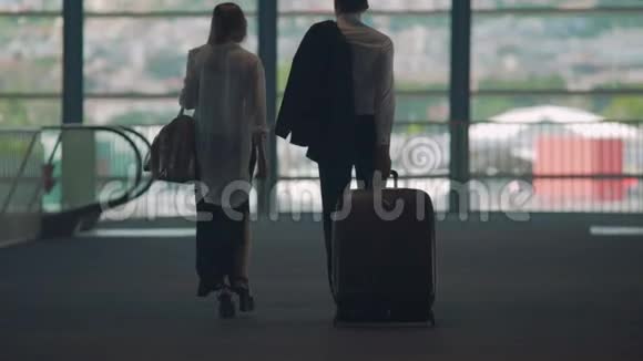 商务伙伴步行至机场自动扶梯携带行李旅游视频的预览图