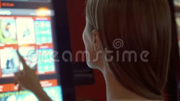 穿红色t恤的年轻美女在电影院的自动售货机买电影票视频的预览图