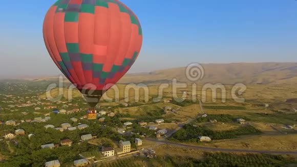 巨大的彩色热气球飞过亚美尼亚村庄风景视频的预览图