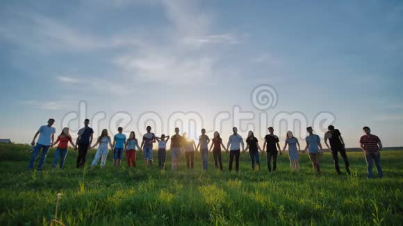 十九个朋友的剪影在日落背景上牵手视频的预览图