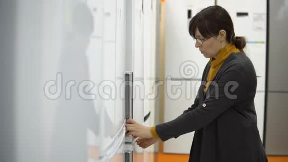 一个年轻的女人在家电店里选择冰箱视频的预览图