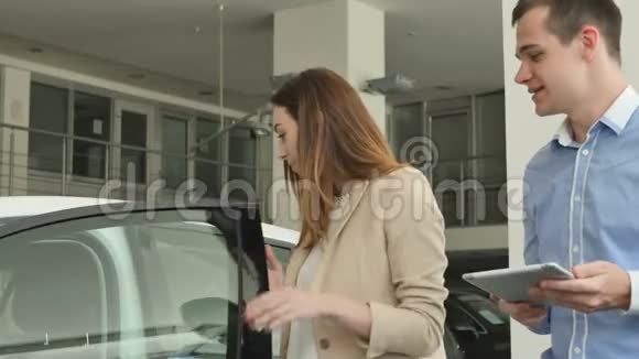 推销员向年轻的女商人展示汽车内饰视频的预览图