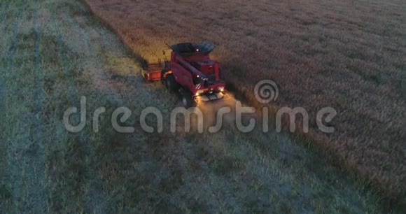 在日落时在一片田野中的联合收割机上方的空中视野拖拉机和农用机械收获视频的预览图