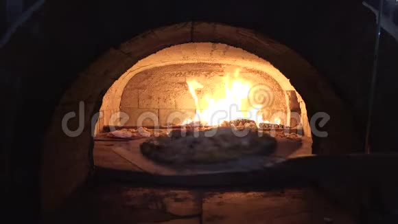 铁锹把比萨饼放进木炉里火焰燃烧得很快视频的预览图
