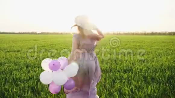 美丽的女孩带着五颜六色的气球在春田里奔跑视频的预览图