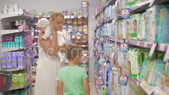 有宝宝的女人和大儿子选择超市里的尿布视频的预览图