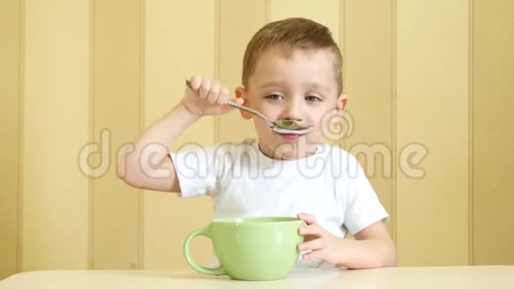 孩子高兴地笑着用勺子从盘子里吃汤坐在桌子旁视频的预览图