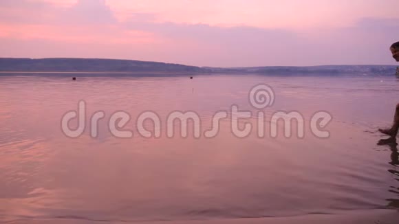 日落时分两个男孩在河滩上一起奔跑视频的预览图