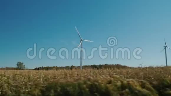沿着田野和风力涡轮机骑行穿过乡村从车窗可以看到视频的预览图