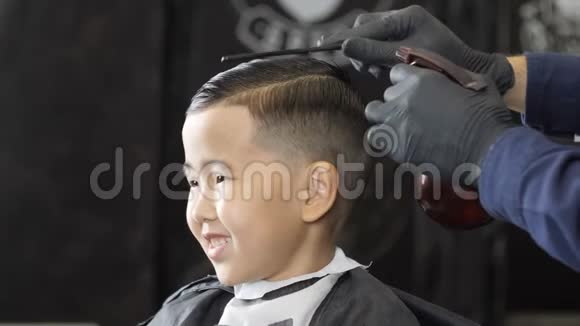 戴黑手套的理发师将水洒在一个亚洲孩子的头发上并以每秒60帧的速度梳头视频的预览图