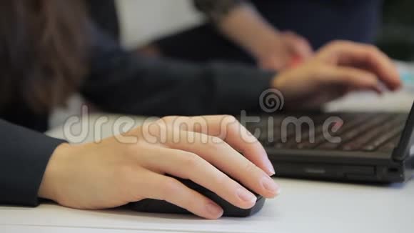 女员工用笔记本电脑工作在现代办公室用手移动鼠标视频的预览图