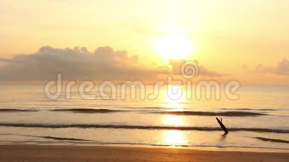 夕阳在黄昏的时候天空的黄色和橙色在海面上慢慢地在热带海滩上波浪视频的预览图