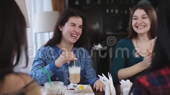 年轻漂亮的女朋友坐在咖啡馆里谈笑风生可爱的女孩喝咖啡和拿铁视频的预览图