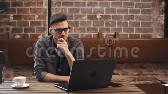 程序员与笔记本电脑坐在咖啡厅视频的预览图
