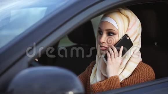 一个穆斯林妇女过着现代的生活方式开车打电话视频的预览图