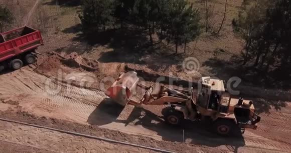 挖掘机将沙子装入卡车工人让路视频的预览图