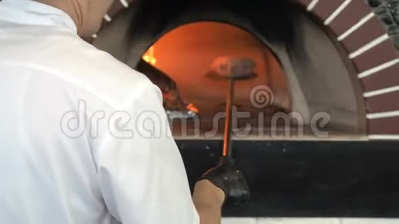无法辨认的男性面包师从面包中取出放入烧木炉中烘焙面包师平底锅视频的预览图