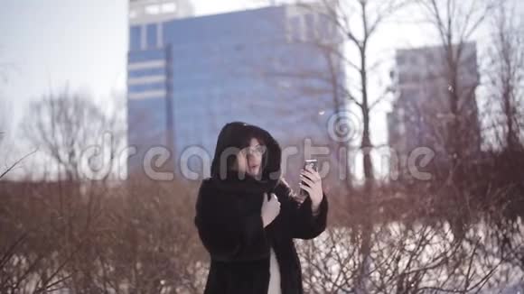 美丽的女人在户外使用智能手机视频聊天冬天和朋友分享旅行冒险视频的预览图